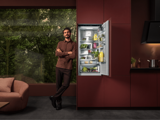 Man standing next to a fridge in a kitchen.